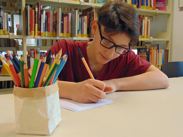 Das Foto zeigt einen Jugendlichen beim Geschichten schreiben in der Stadtbücherei Elmshorn.