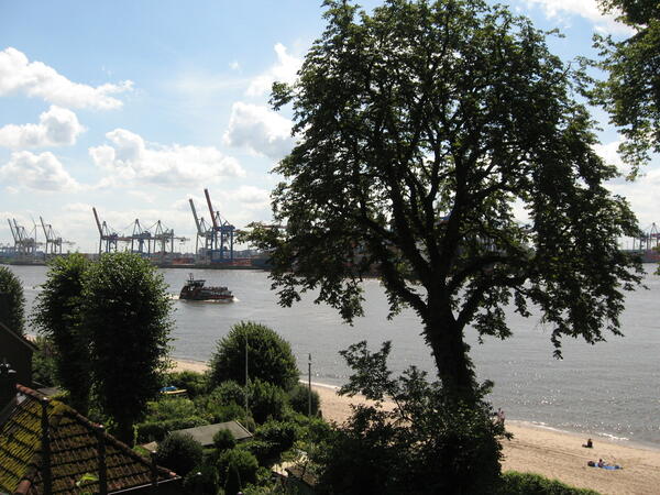 Ein Überblick über die Elbe in Hamburg. Im Hintergund befinden sich große Kräne und ein Ausflugsschiff.