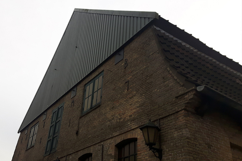 Vorderansicht eines Fabrikgebäudes mit Spitzdach.