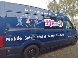 Ein blauer Transporter mit buntem Logo und skizzierten spielenden Kindern.