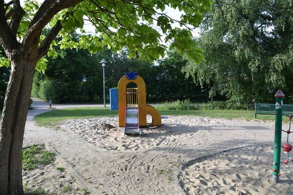 Eine kleine Kinderrutsche steht auf einem Sandplatz.