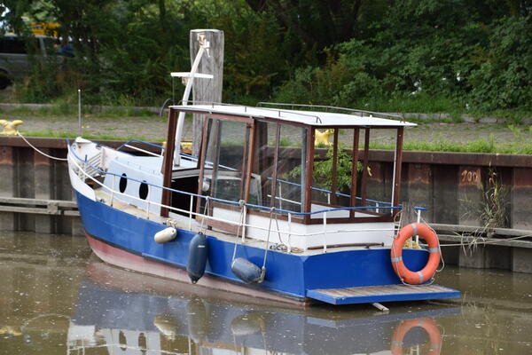 Ein kleines, blaues Motorboot mit Kajüte fährt auf der Krückau im Elmshorner Hafen.