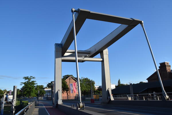 Die Käpten-Jürs-Brücke ist eine Klappbrücke die über die Krückau führt. Die Stahlträger Konstruktion der Brücke ragen vor einem blauen Himmel in die Höhe.