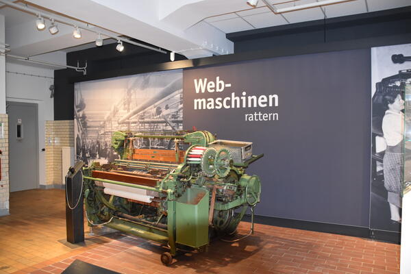 Eine alte, schwere Webmaschine mit einem angefangenen Webstück.