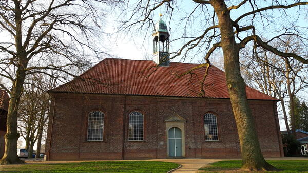 Bild vergr&ouml;&szlig;ern: Backsteinkirche mit kleinem Glockenturm auf dem rot geziegeltem Dach.