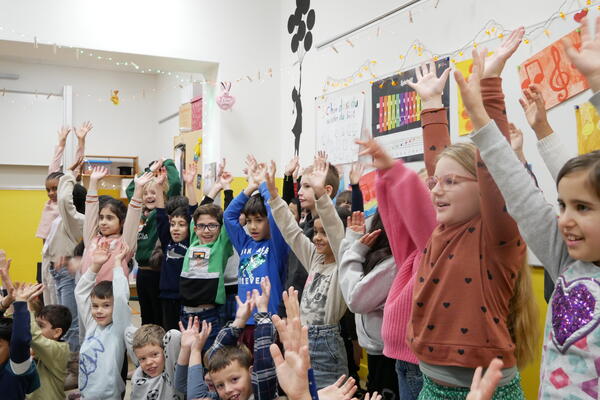 Kinder in einem Unterrichtsraum halten die Hände hoch