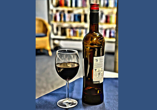 Halbvolles Weinglas und Weinflasche auf einem Beistelltisch